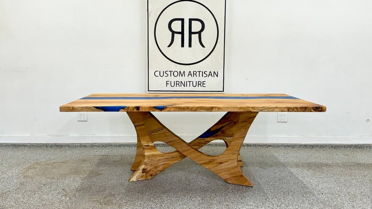 A spalted maple table with a blue river on a crossed sculptural wood base
